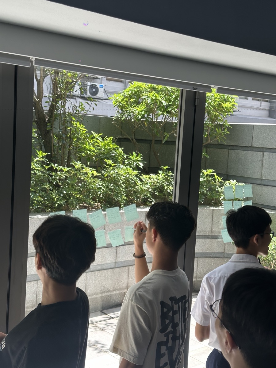 Students arranging sticky notes on glass — design-thinking moment